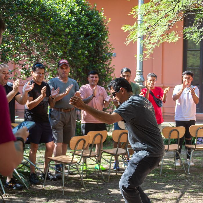 Un estudiante baila en el centro mientras sus compañeros aplauden, en la dinámica de llegada