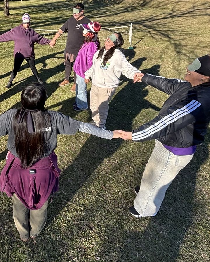 Estudiantes tomados de la mano en ronda, sobre el pasto